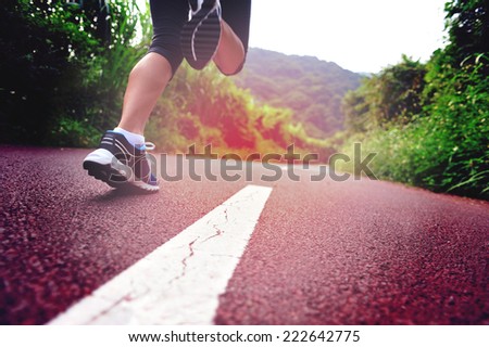 young fitness woman legs running at forest trail