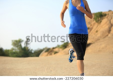 young woman runner legs running on mountain trail