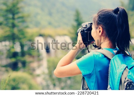 woman tourist/photographer taking photo with digital camera in jiuzhaigou national park,china