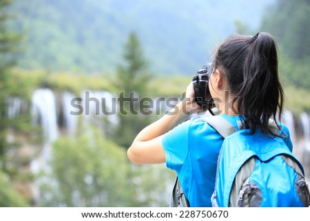 woman tourist/photographe taking photo with digital camera in jiuzhaigou national park,china