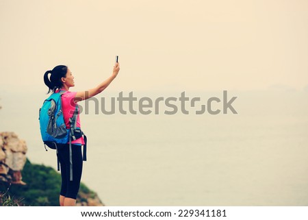 woman hiker taking self photo on sunrise seaside