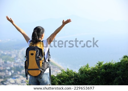 cheering asian woman hiker winning open arms to sea