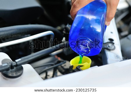 hands adding auto glass cleaner for car