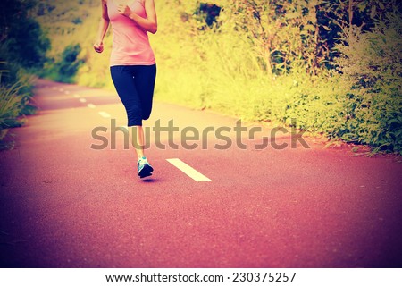 young fitness asian woman running at forest trail