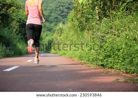 young fit Asian woman running on forest trail