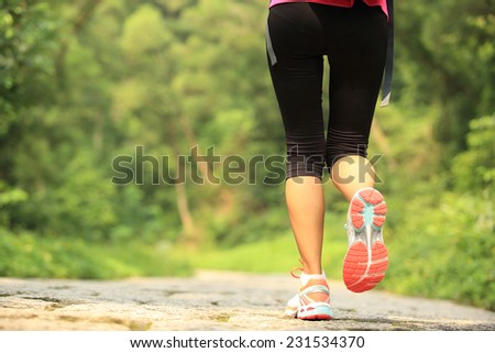 young fitness woman legs walking on forest trail