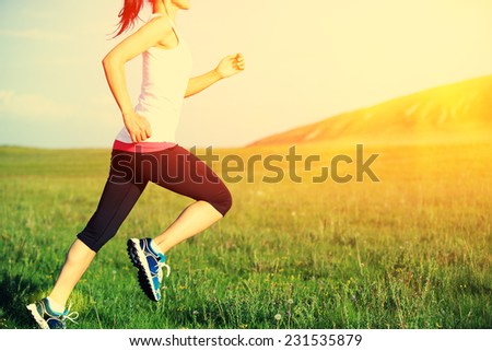 Runner athlete running on grass seaside. woman fitness sunrise/sunset jogging workout wellness concept.