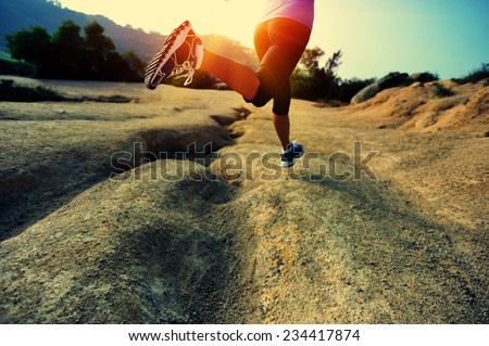 young woman runner legs running on mountain trail