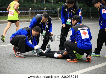 SHENZHEN,CHINA - DECEMBER 7: Medical support help a injured marathon runner\'s legs on the street  at Shenzhen International Marathon DECEMBER 7, 2014 in Shenzhen, China