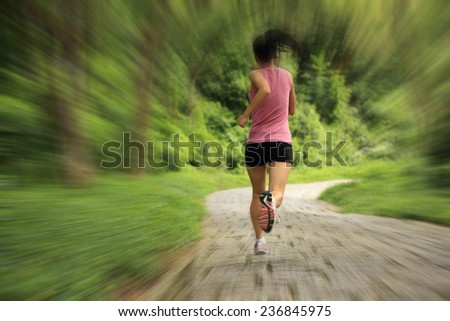 young fitness woman running at forest trail