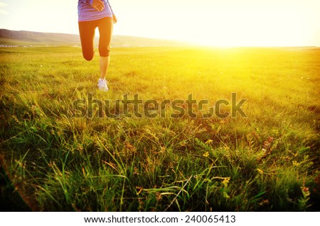 Runner athlete legs running on grass seaside. woman fitness sunrise/sunset jogging workout wellness concept.