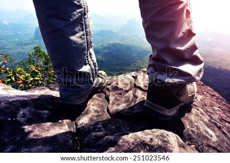 young woman hiker stand on mountain peak cliff