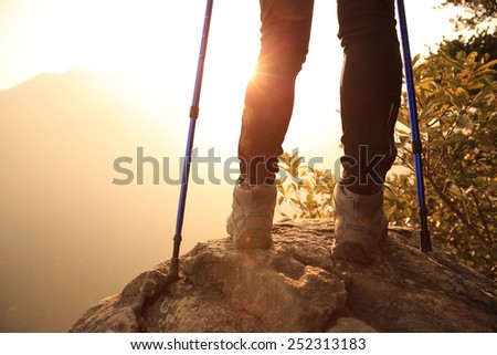 woman hiker legs stand on mountain peak rock