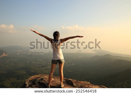 cheering woman open arms at mountain peak