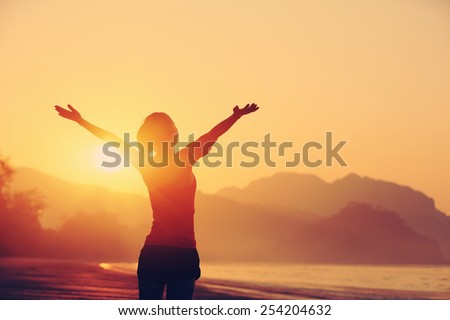 strong confidence woman open arms under the sunrise at seaside