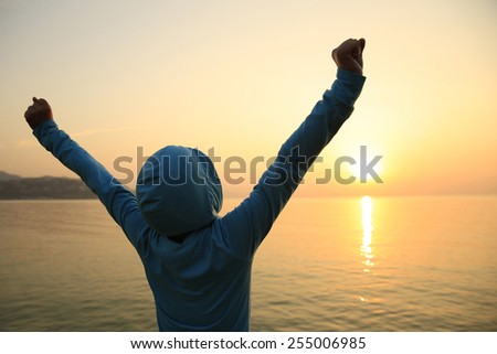 cheering woman open arms at sunrise seaside