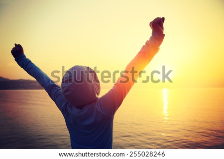 cheering woman open arms at sunrise seaside