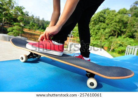skateboarding woman tying shoelace at skatepark