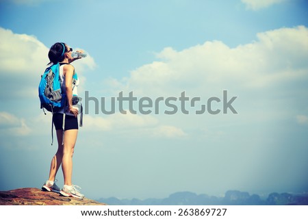 woman hiker drink water at mountain peak cliff