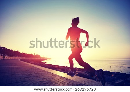 young woman runner running at seaside. woman fitness silhouette sunrise jogging workout wellness concept.