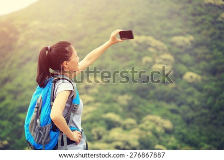 young woman hiker taking photo with smartphone mountain peak