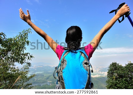 young cheering woman hiker open arms at mountain peak