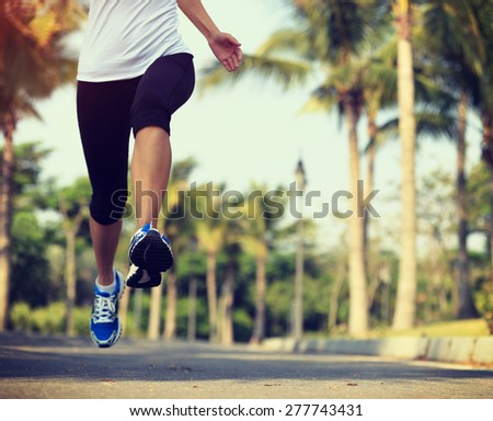 fitness jogger legs running at tropical park. woman fitness jogging workout wellness concept.