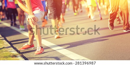 Marathon runner stretching legs on city road