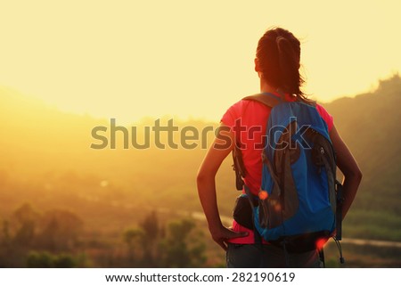 young woman hiker enjoy the view at sunrise mountain peak