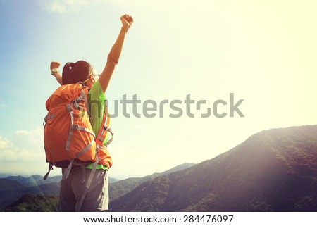 cheering woman hiker open arms at mountain peak