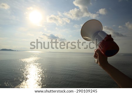 hand hold megaphone  under sunrise seaside twilight sky