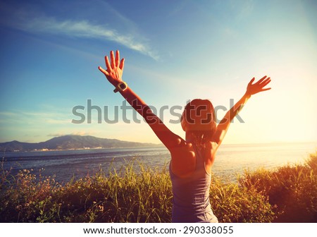 young cheering woman open arms at sunrise seaside