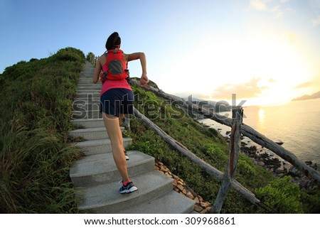 fitness woman runner trail running on seaside mountain stairs, training for cross country running.