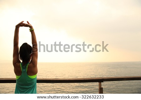 fitness sports woman runner stretching on wooden boardwalk seaside