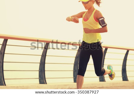 young fitness woman runner checking her running time from smart watch at seaside
