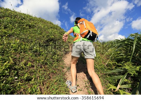 young woman backpacker climbing to mountain peak