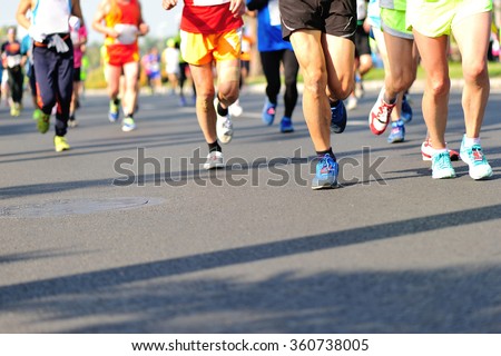 Unidentified marathon athletes legs running on city road