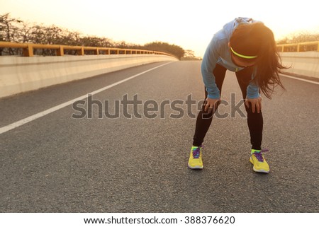 tired woman runner taking a rest after running hard on city road