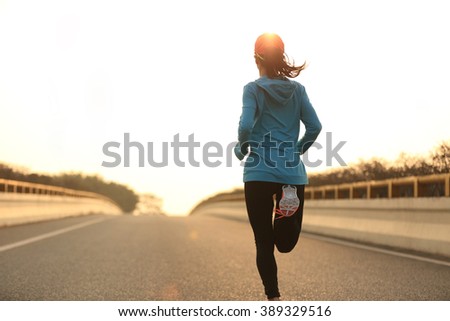 young woman runner athlete running at sunrise city road