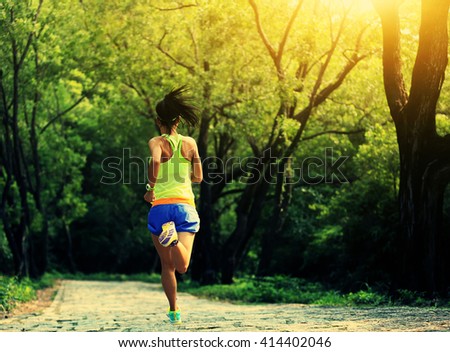 young fitness woman trail runner running in forest