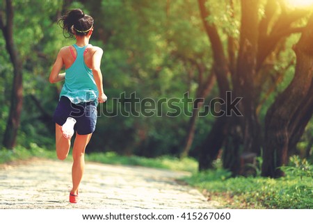 young woman trail runner running at forest stone trail