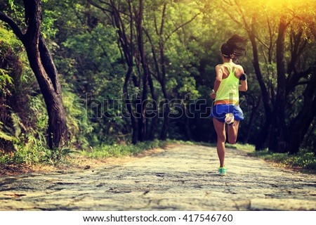 young fitness woman trail runner running on forest