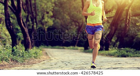 young fitness woman trail runner running in forest