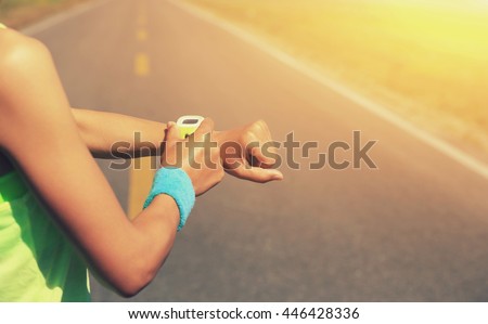 young woman runner ready to run set and looking at sports smart watch, checking performance or heart rate pulse trace. sport and fitness outdoors .