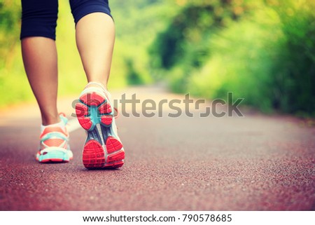 Young fitness female runner legs ready for run on forest trail