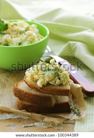 egg salad in a green cup with black bread