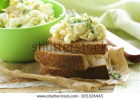 egg salad in a green cup with black bread