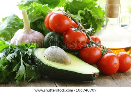 avocado, tomato, lettuce and oil on a wooden table