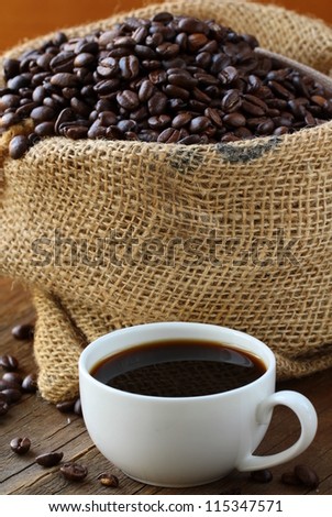 Linen bag of coffee beans and a cup of espresso on a wooden table