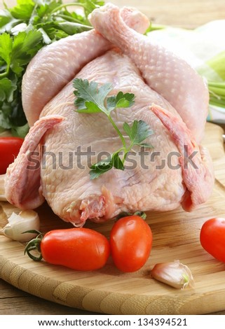 fresh raw chicken on a cutting board with vegetables and herbs